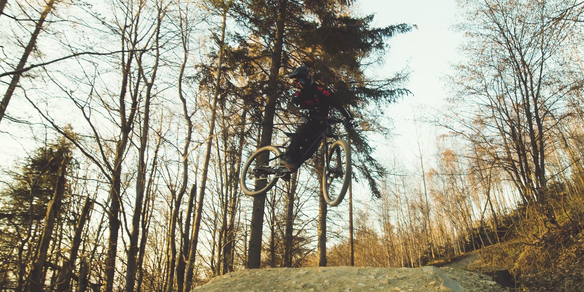 Mountain biker jumping a dirt ramp.